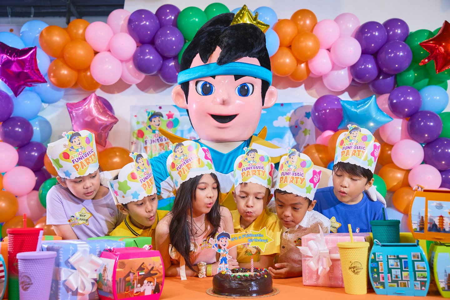 Kinderen met feestmutsen verzamelen zich rond een verjaardagstaart.