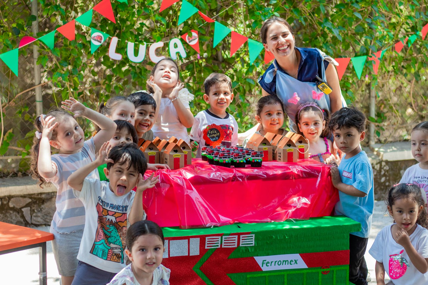 Een vrouw en een groep kinderen verzamelen zich rond een feestelijke buitentafel.