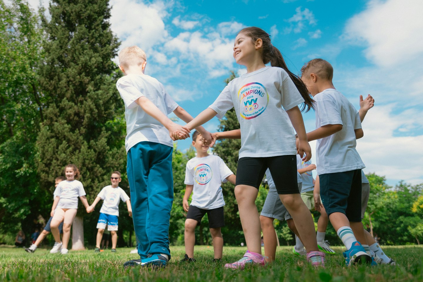 Kinderen in bijpassende shirts houden elkaars hand vast tijdens het buitenspelen.