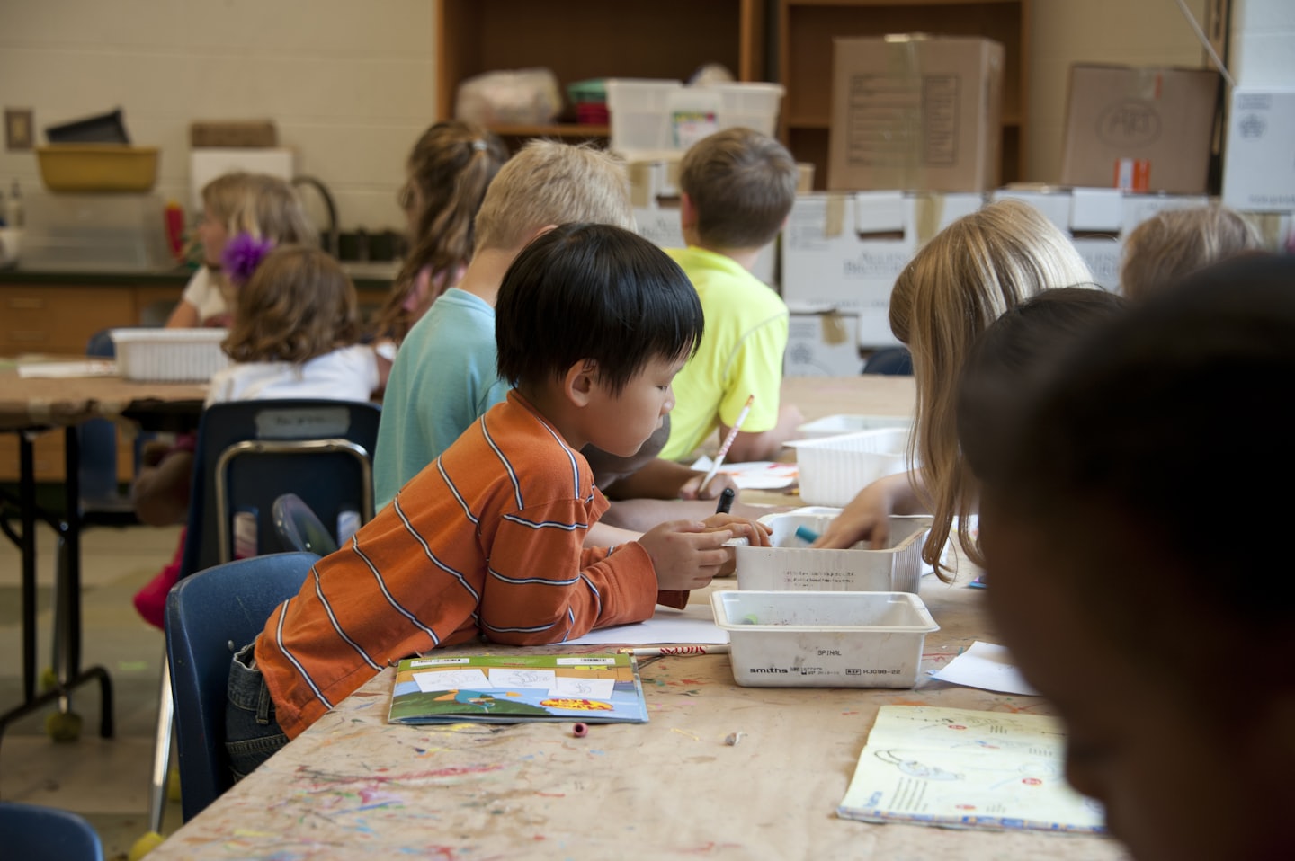 Diverse kinderen werken aan knutselprojecten aan een tafel in een klaslokaal.