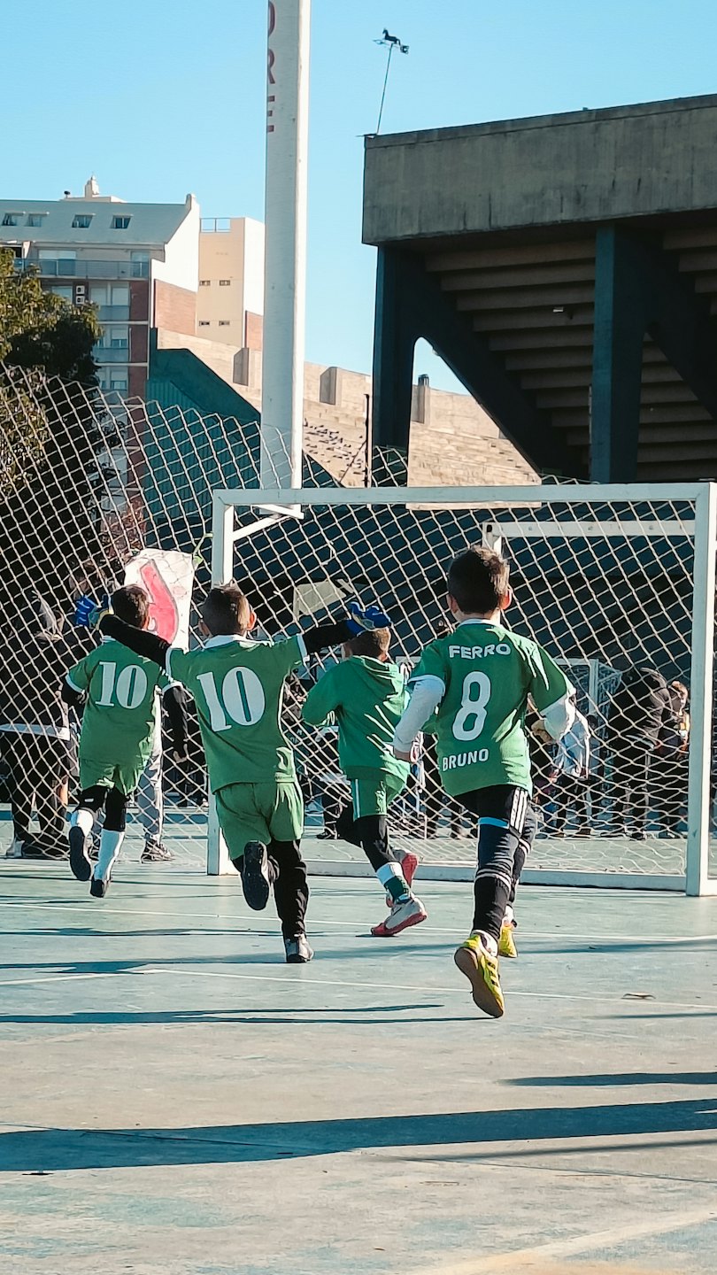 Vier kinderen in voetbaltenues rennen naar een doel.