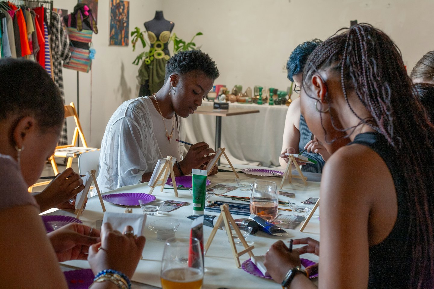Diverse groep mensen schildert op doeken aan een tafel in een kunstworkshop.
